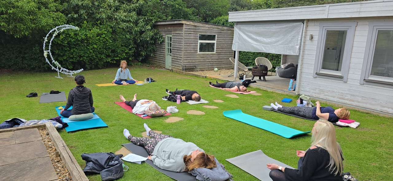 An outdoor yoga session in a green garden setting.